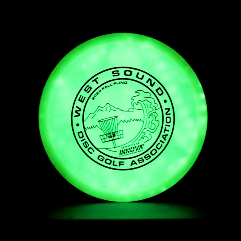 A glowing green disc golf disc with a black logo sits centered against a solid black background.