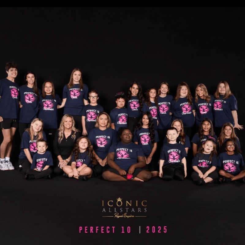 A group of cheerleaders in navy blue shirts poses together against a solid black background.