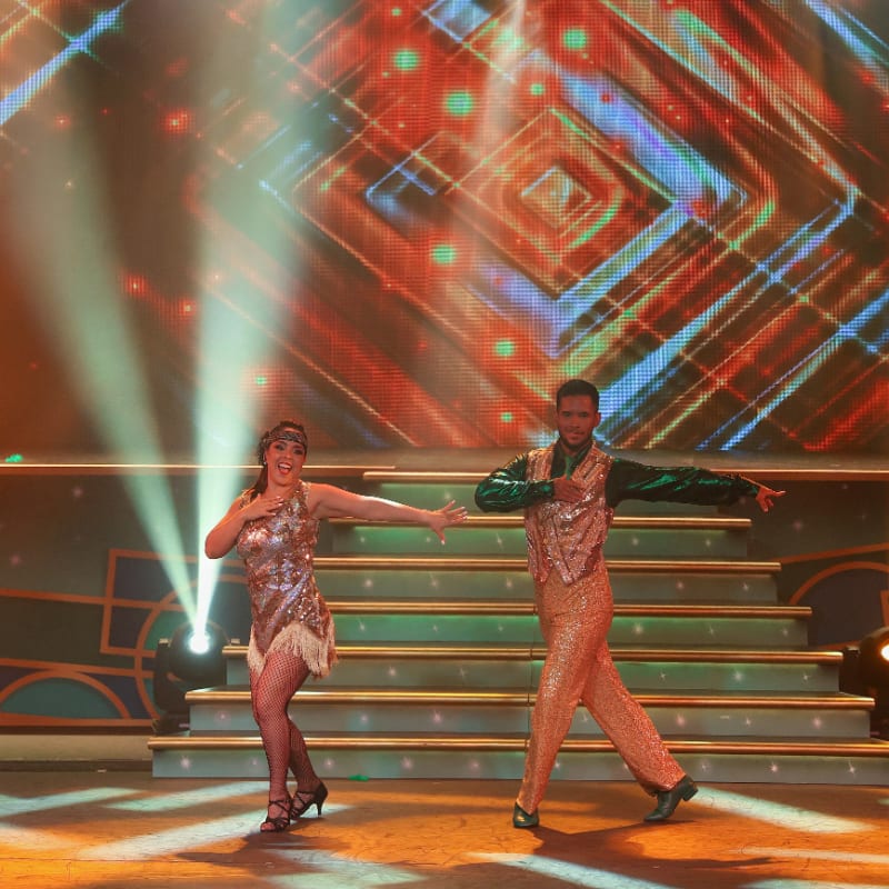 Dancers performing a routine on a vibrant, illuminated stage