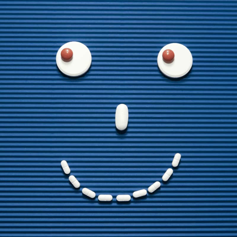 A smiley face made out of pills on a blue background
