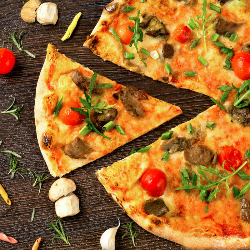 pizza with tomato and green leaves on white ceramic plate
