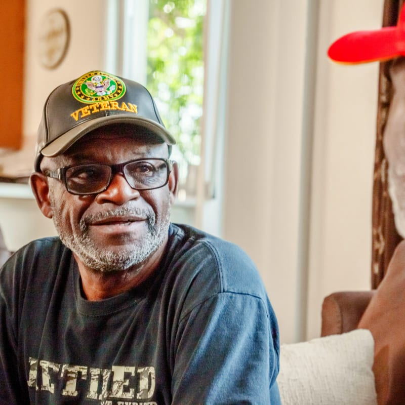 Two men talking, one wears a veteran hat
