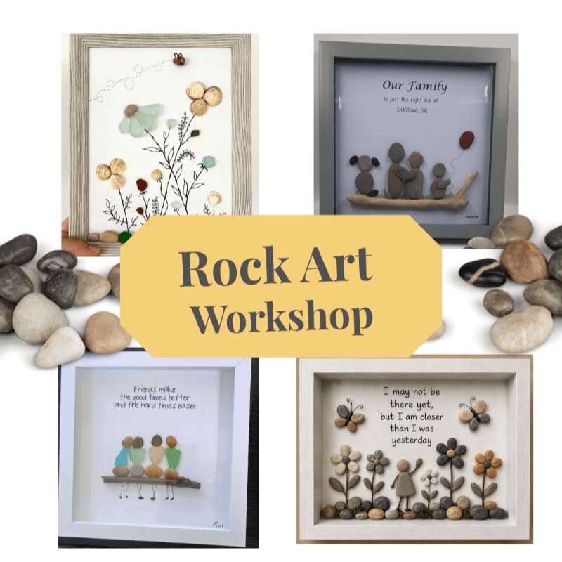 A yellow "Rock Art Workshop" sign is centered over four framed pebble art pieces, with scattered smooth stones in the foreground.
