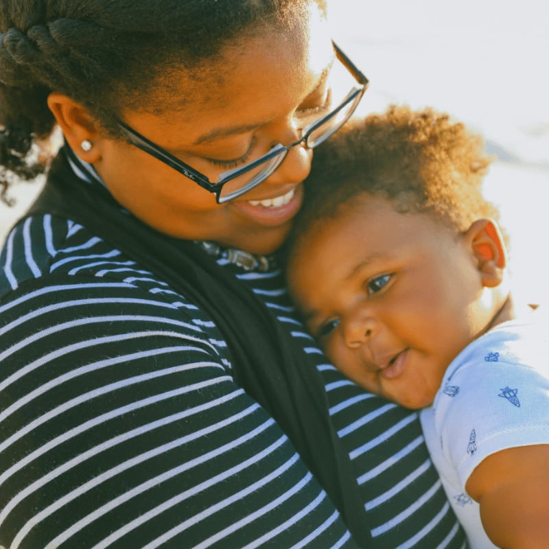man in black and white striped shirt carrying baby in white and blue onesie