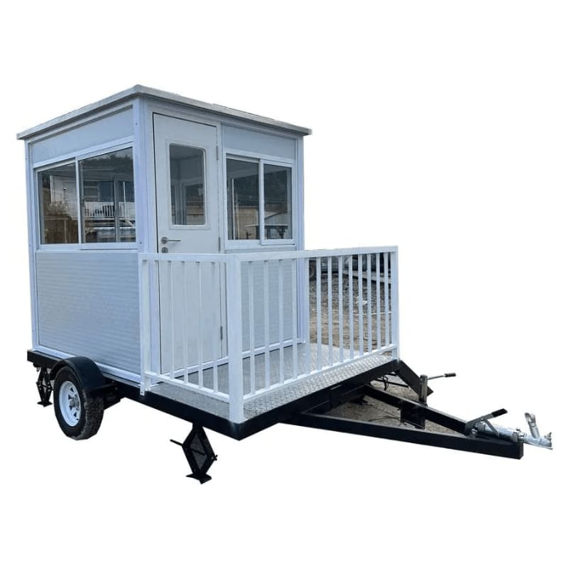 A small white portable cabin with a deck sits on a black trailer against a plain white background.