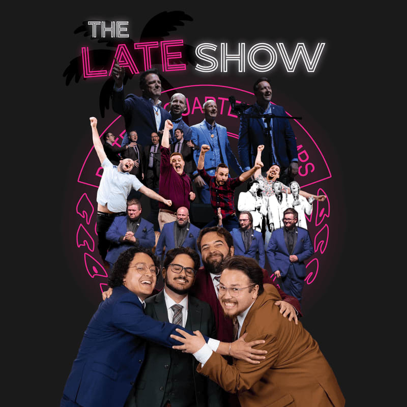 A group of smiling men in suits and casual wear pose together in the foreground against a dark background featuring a pink circular graphic and the text "THE LATE SHOW."