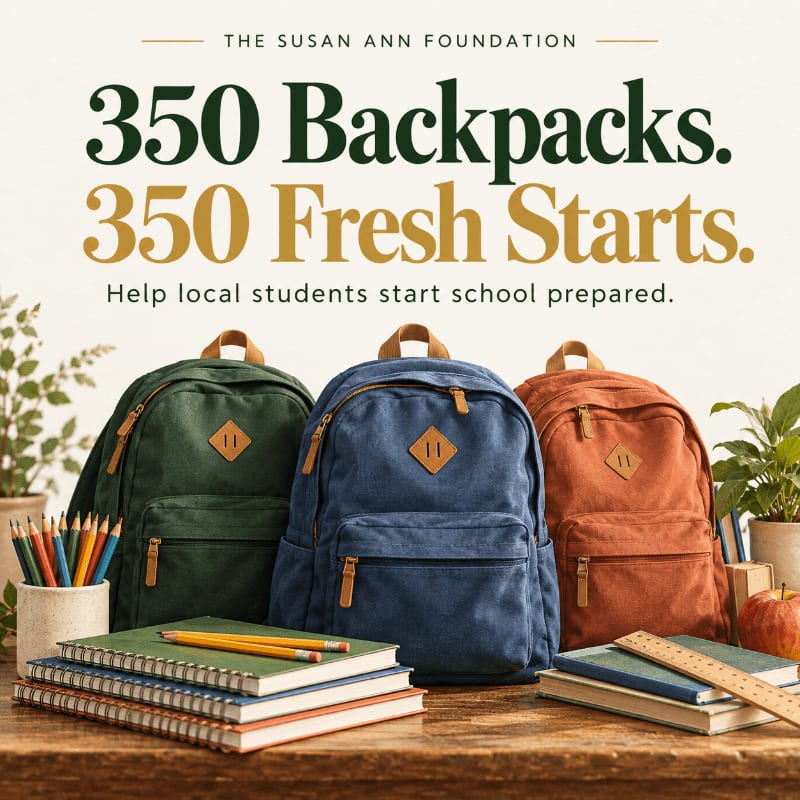 Three colorful backpacks stand on a wooden table surrounded by notebooks and pencils, set against a light background with promotional text for The Susan Ann Foundation.