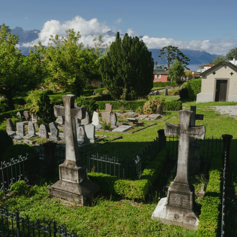 A sunny cemetery with gravestones and a small building