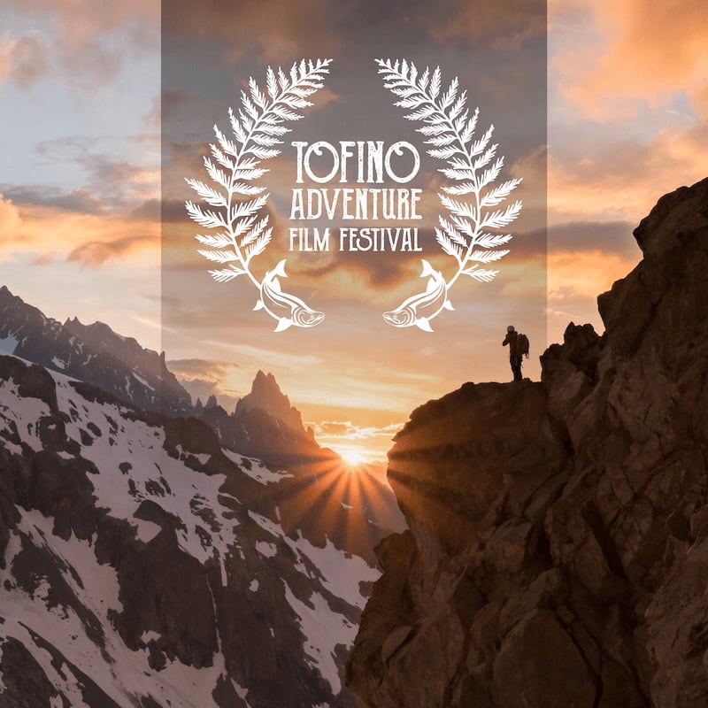 A hiker stands atop a rocky cliff in the foreground, overlooking a snowy mountain range under a sunset sky with a Tofino Adventure Film Festival logo overlaid in the center.