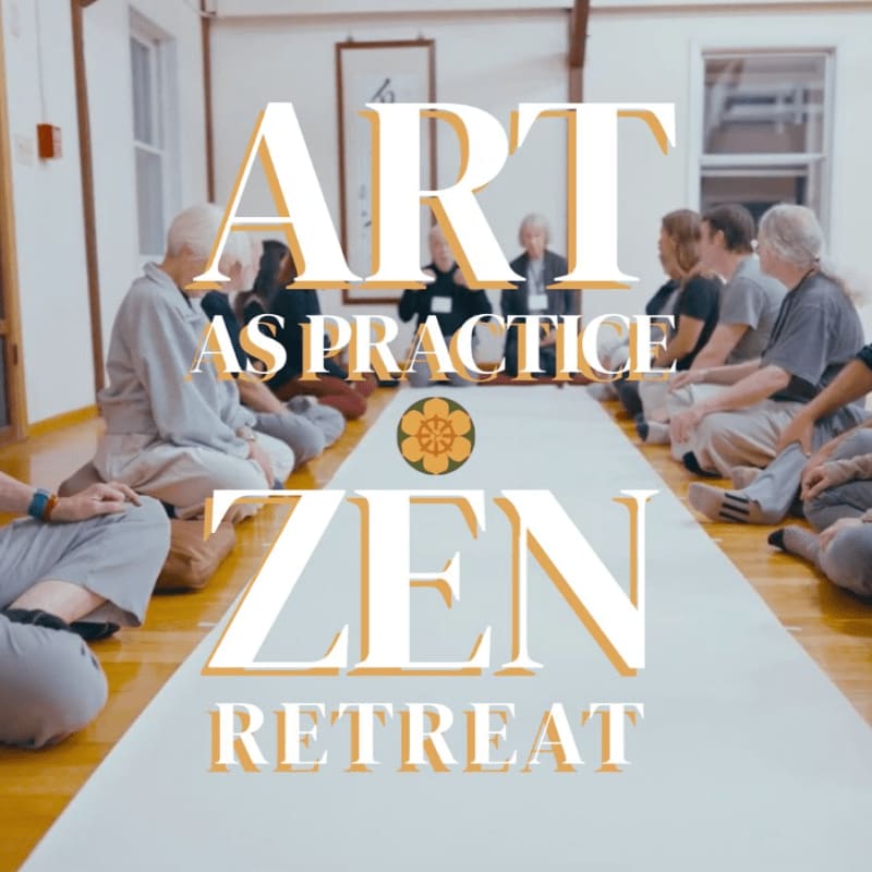 People sit in meditation on a white mat in a bright room with white walls.