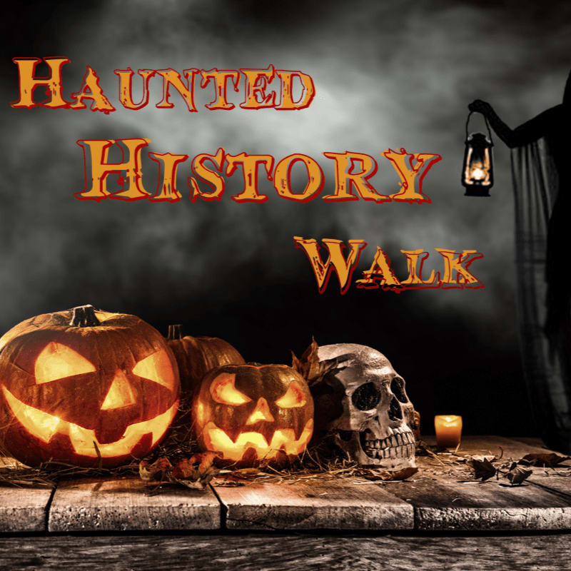 Glowing jack-o'-lanterns and a skull sit on a wooden surface in the foreground, while a cloaked figure holding a lantern stands against a dark, misty background with the text "HAUNTED HISTORY WALK."
