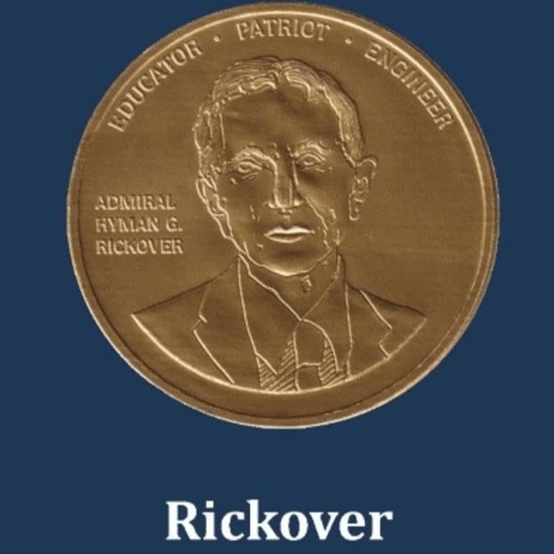A gold medal featuring the portrait of Admiral Hyman G. Rickover is centered against a solid dark blue background.