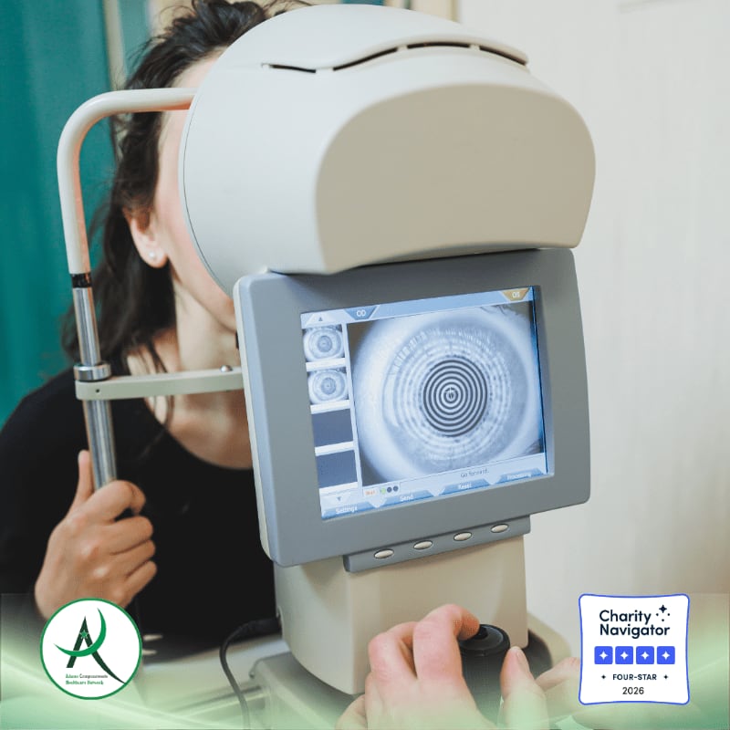 A woman is being examined by a specialized eye-scanning device in a clinical setting.