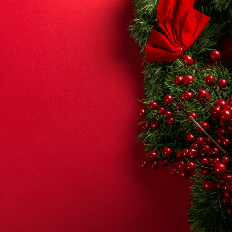 a close up of a christmas wreath on a red background