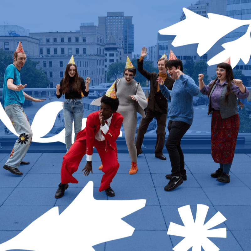 A group of people wearing party hats dance on a blue rooftop with a city skyline in the background, framed by white graphic overlays.
