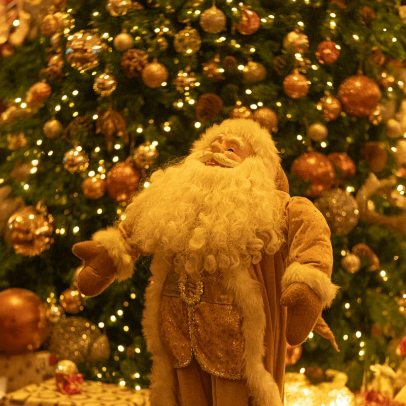 a santa clause standing in front of a christmas tree