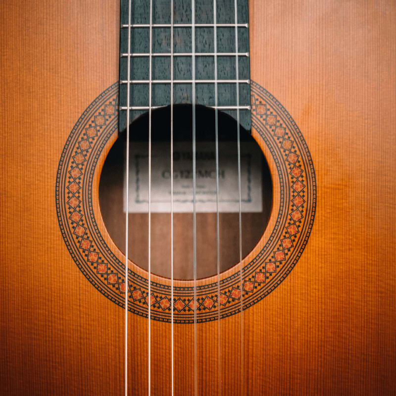 brown acoustic guitar on brown wooden surface
