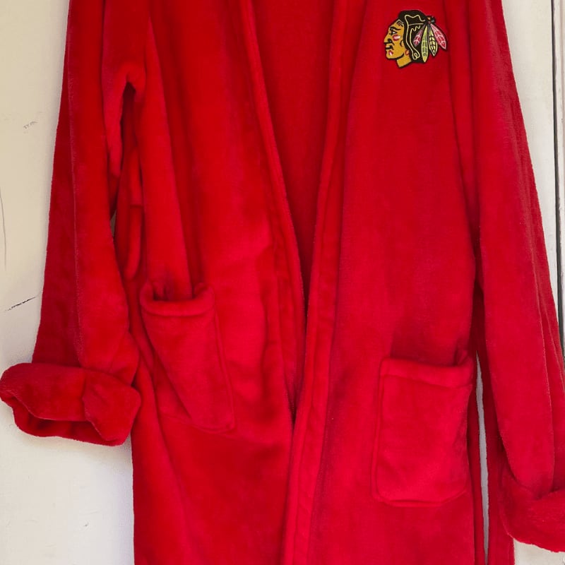 A red plush robe with a Chicago Blackhawks logo is set against a plain white background.