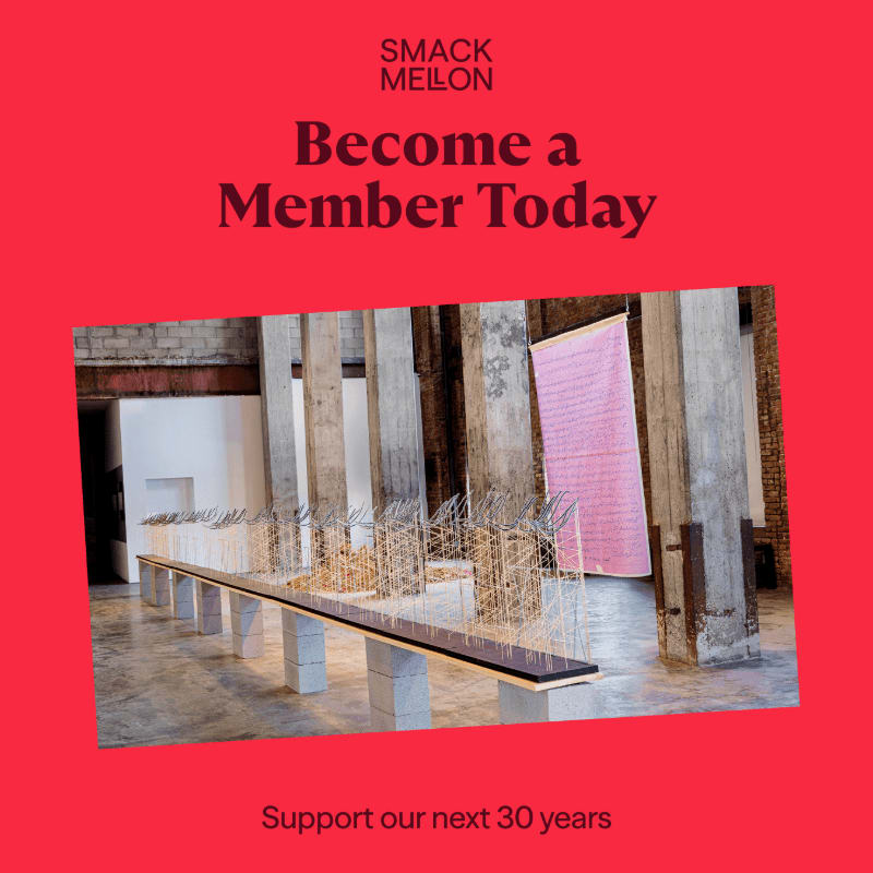 A long, thin art installation with wire structures sits in the foreground of an industrial gallery space with concrete pillars and a pink hanging fabric in the background.