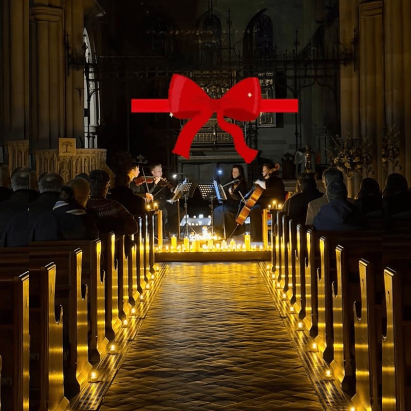 A large red bow floats above a musical performance in a candlelit church aisle.