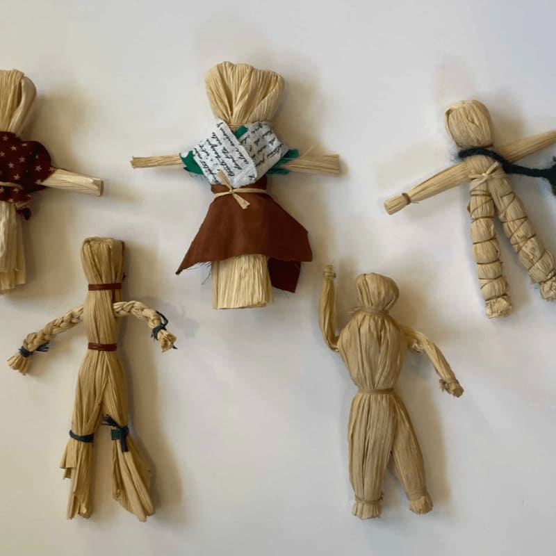 Five small straw figures are arranged on a plain white background.