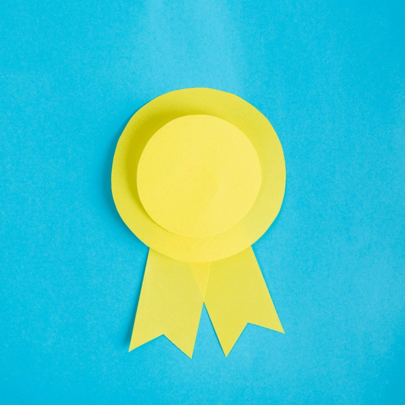 A yellow paper award ribbon on a bright blue background