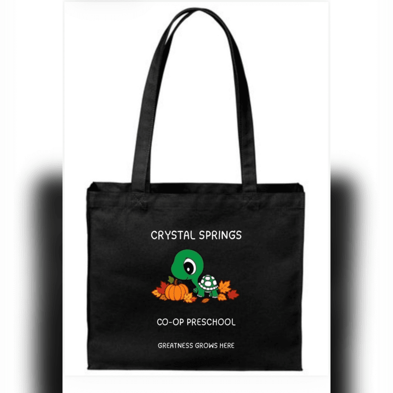 A black tote bag featuring a cute turtle and pumpkin graphic with "Crystal Springs Co-Op Preschool" text is centered against a plain white background.