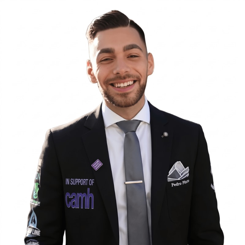 A smiling man in a dark suit and grey tie stands against a plain white background.