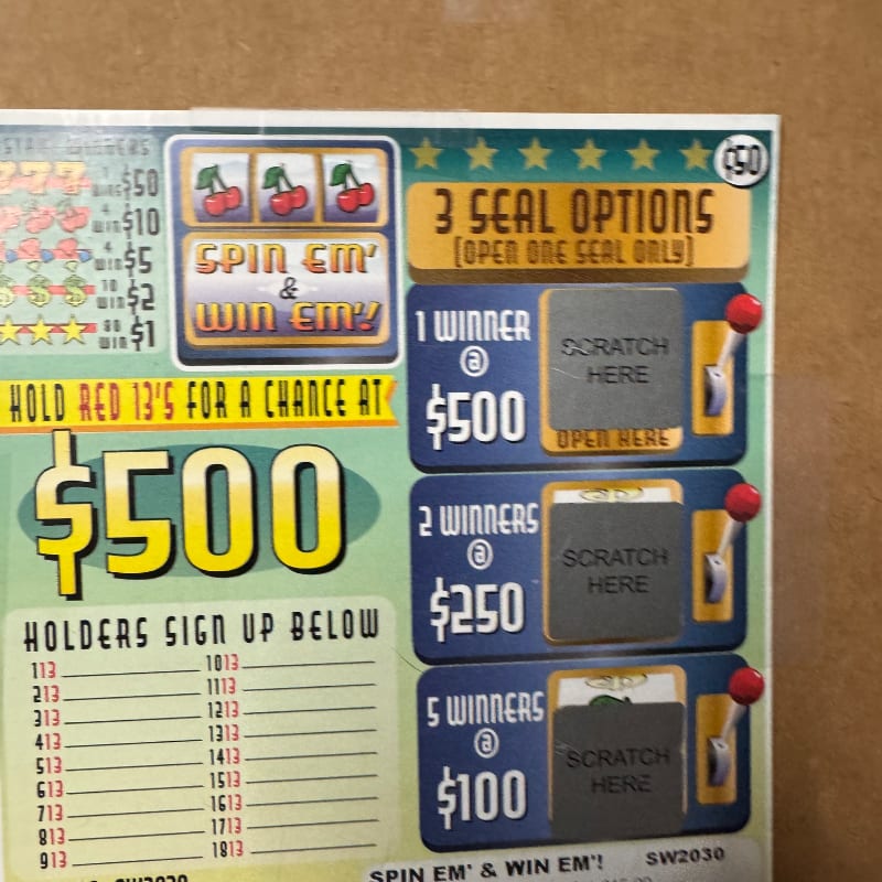 A colorful lottery-style game card with scratch-off sections and a $500 prize announcement sits against a plain brown background.
