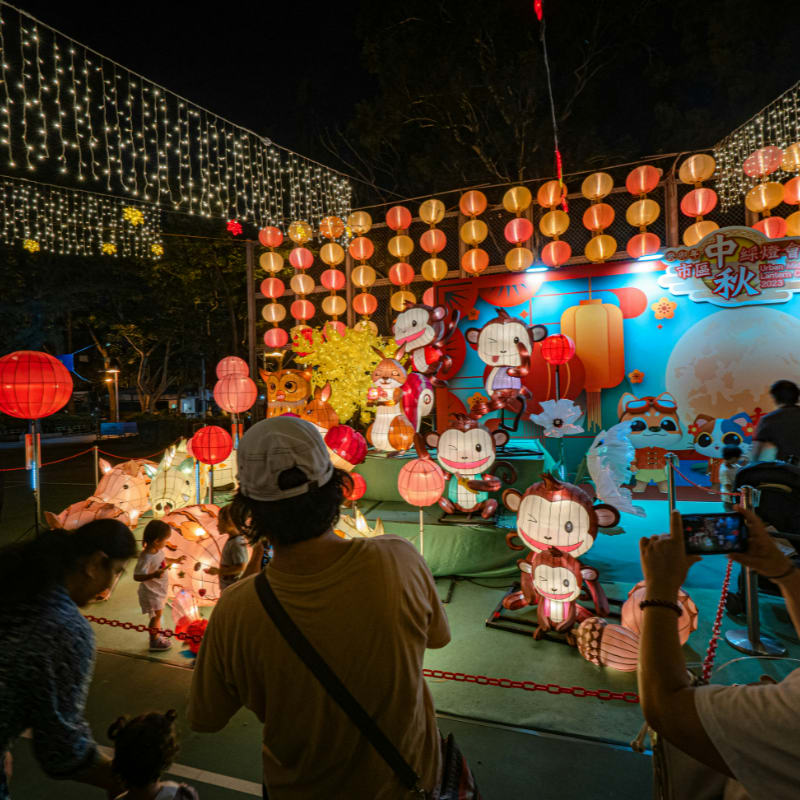 People viewing illuminated animal lanterns at an outdoor Mid-Autumn festival celebration at night