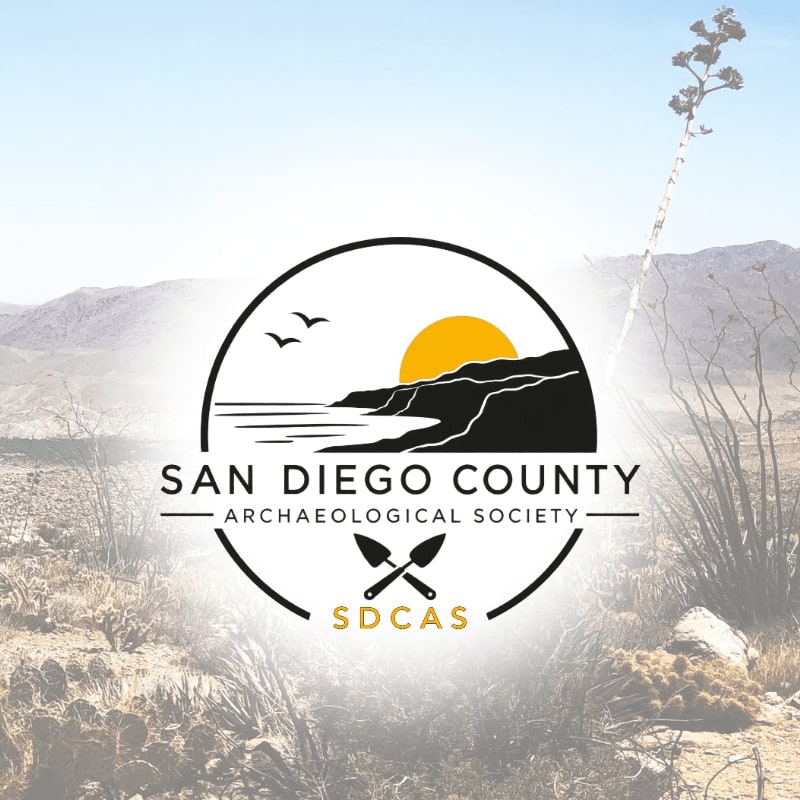 A logo for the San Diego County Archaeological Society is centered in the foreground over a blurred background of a desert landscape with mountains.