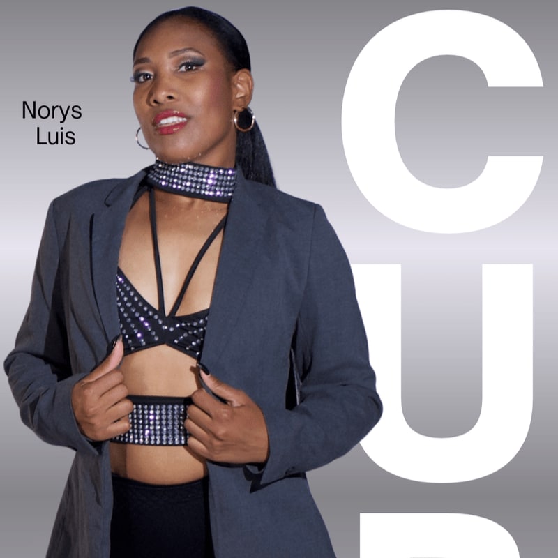 A woman wearing a grey blazer over a sparkling black outfit stands against a grey background with large white letters.