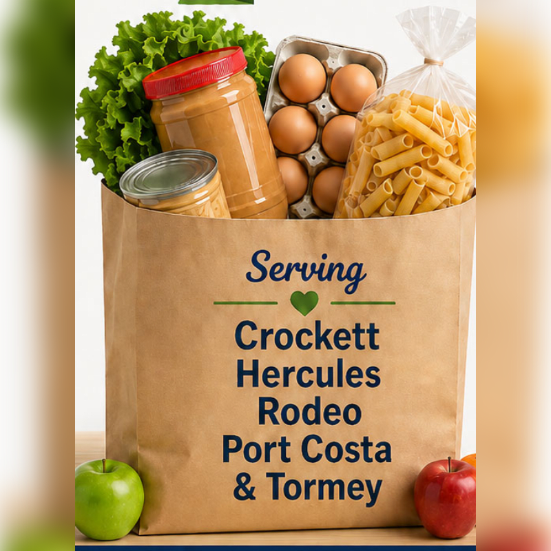 A brown paper grocery bag filled with pasta, eggs, peanut butter, and lettuce sits on a wooden surface with apples in the foreground against a blurred background.