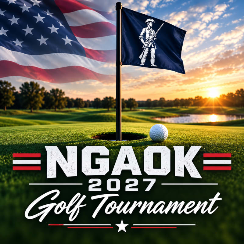 A golf ball sits near a hole on a green in the foreground, with an American flag and a blue military flag waving against a sunset landscape in the background.