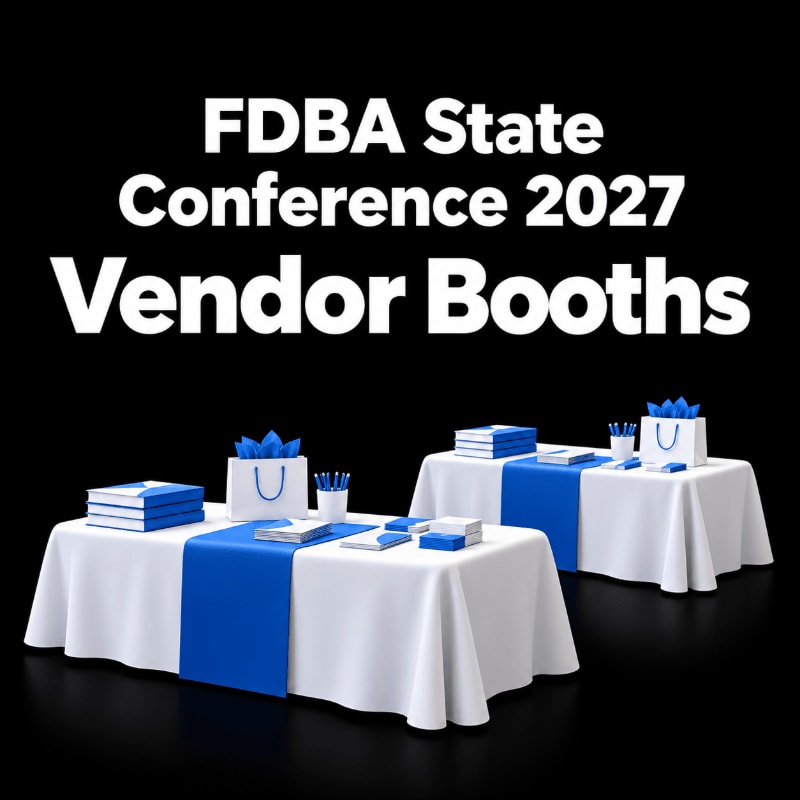 Two white tables with blue runners and promotional materials sit in the foreground against a solid black background featuring bold white text.