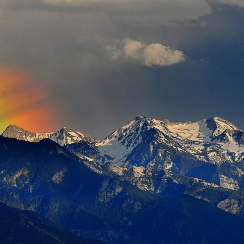 a rainbow in the sky over a mountain range