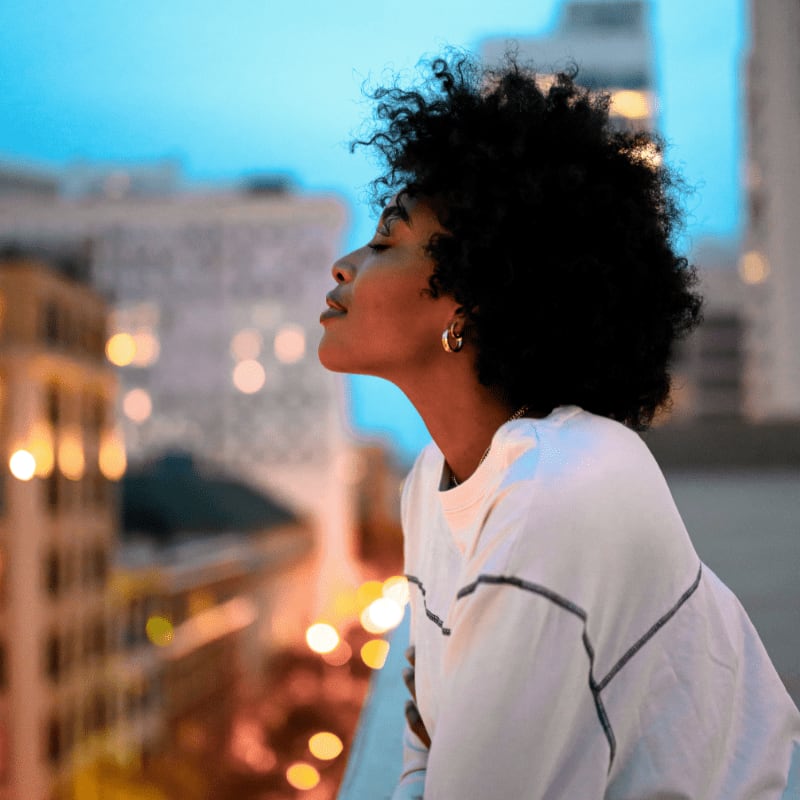 woman in white collared shirt looking at the city during night time