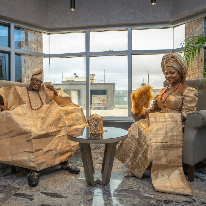 a couple of women sitting on a couch in a room with a large window