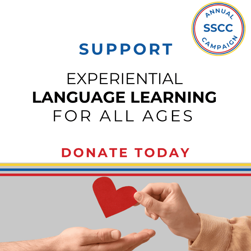 A hand places a red paper heart into another open palm against a grey background, with a white upper section featuring text and a campaign logo.