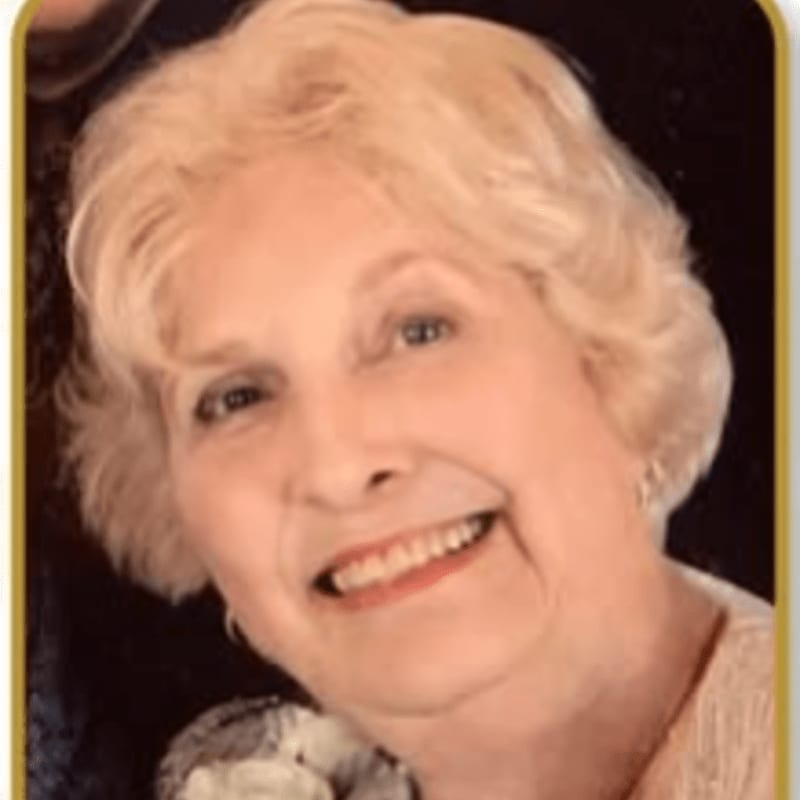 A smiling elderly woman with blonde hair is positioned in the foreground against a dark, blurred background.