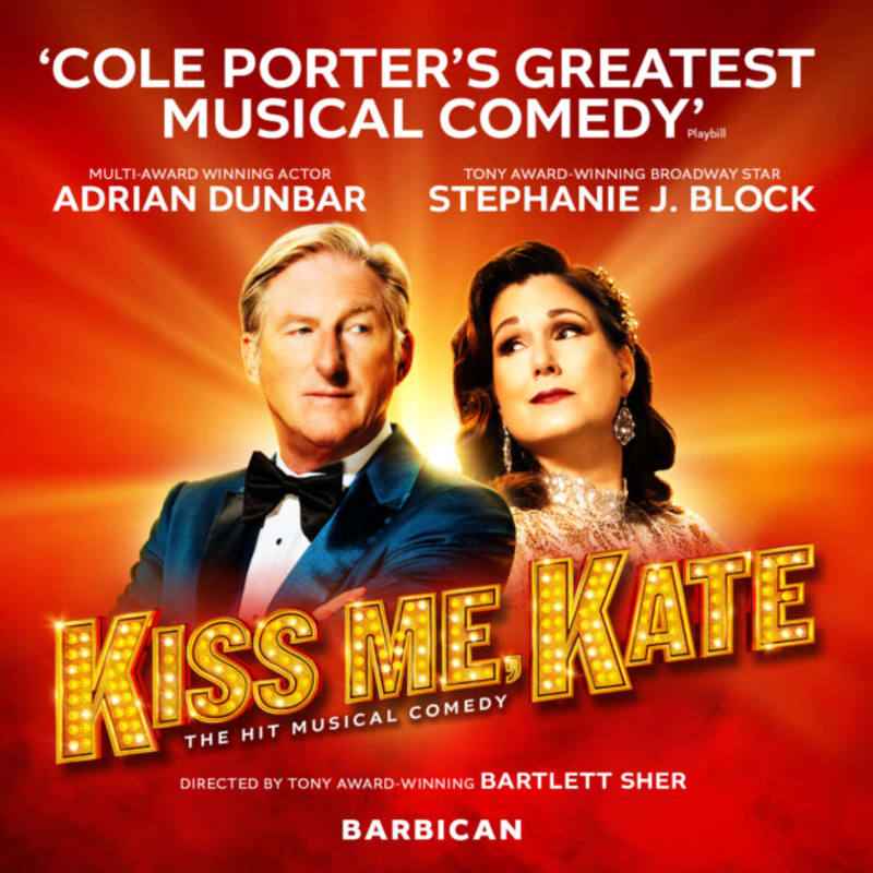 A man in a tuxedo and a woman in an elegant gown stand before a glowing red and orange background on a promotional poster for the musical "Kiss Me, Kate."