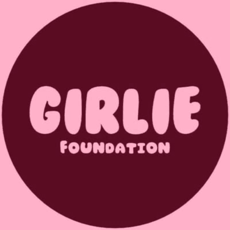 Pink text reading "GIRLIE FOUNDATION" is centered within a dark maroon circle against a light pink background.