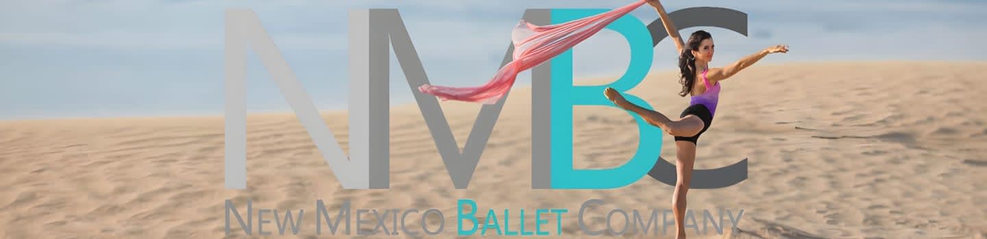 A young ballerina performs a graceful pose on a sandy dune with a pink fabric flowing behind her, set against a pale blue sky.