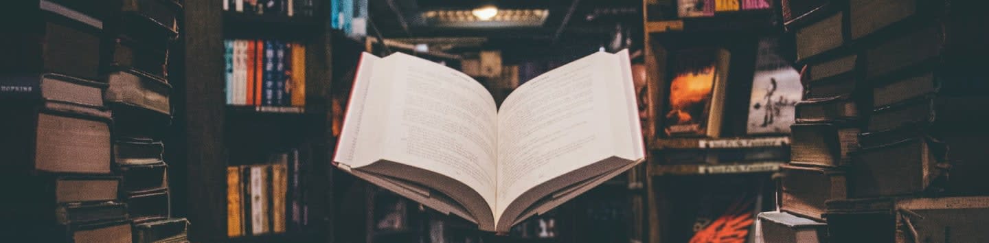view of floating open book from stacked books in library
