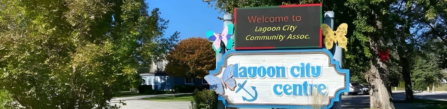 Lush green trees frame a sign welcoming visitors to "Lagoon City Centre" with a building visible in the background.
