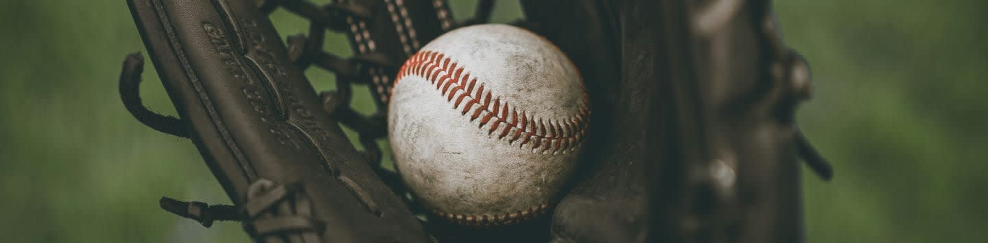 person holding baseball ball in black leather baseball mitt