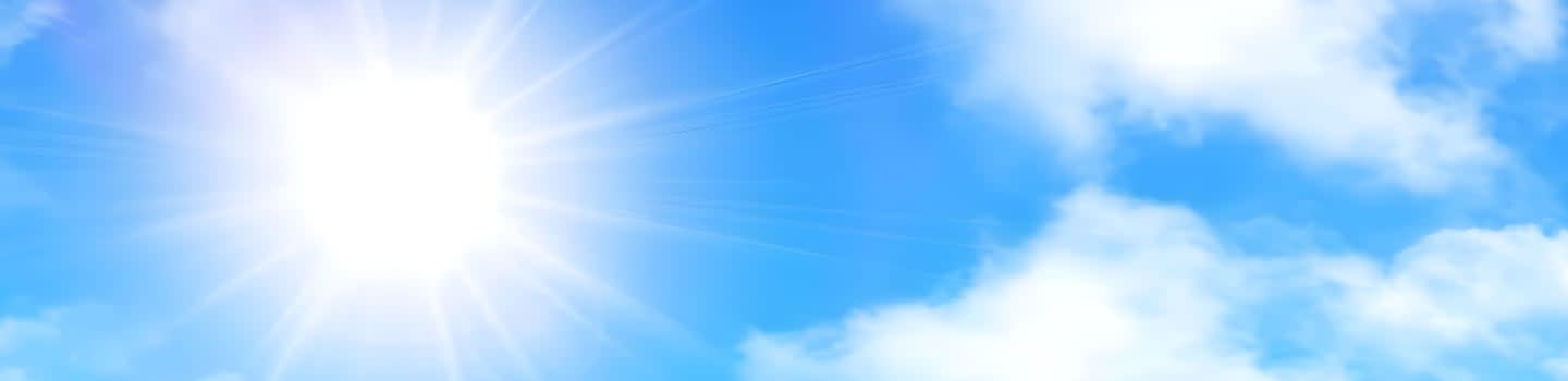 A bright sun shines in the upper left corner of a blue sky filled with fluffy white clouds.