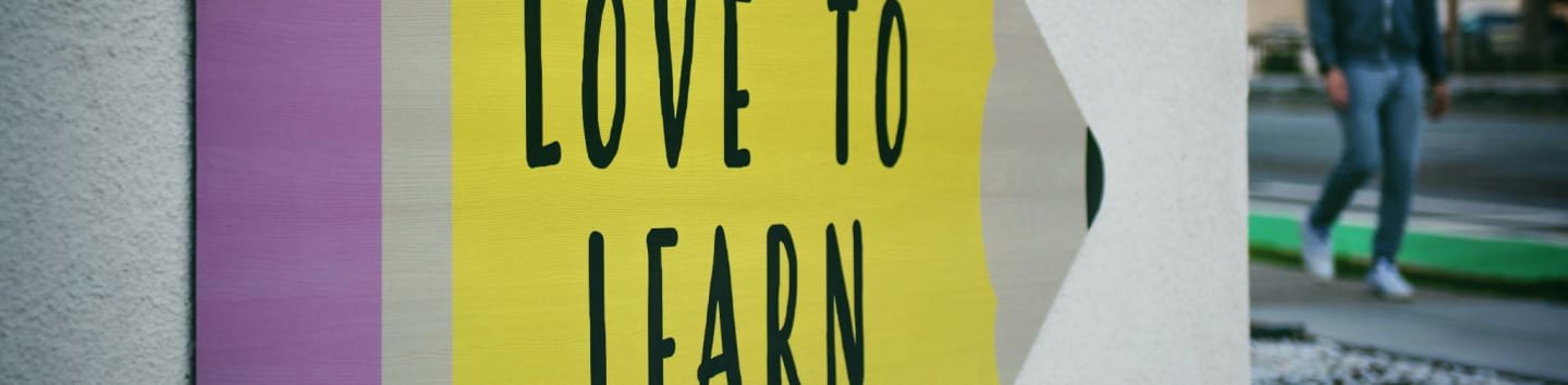 love to learn pencil signage on wall near walking man