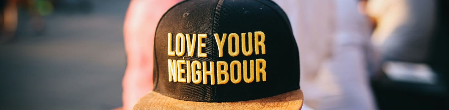 man wearing black cap with love your neighbour print during daytime