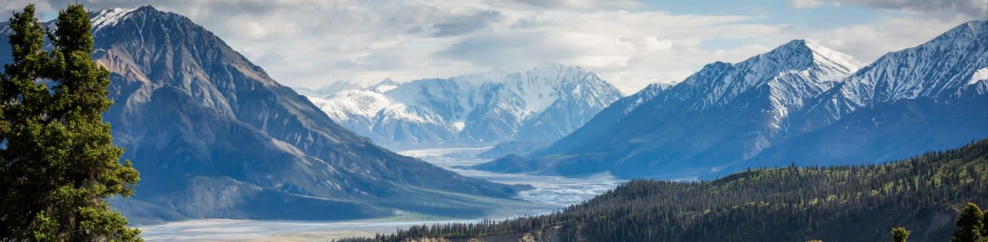 snow capped mountains with valley and forest